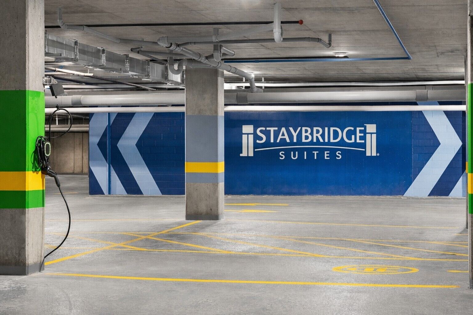 Pysäköintihalli, jossa on Staybridge Suites -ketjun tunnusmerkit, betonipilarit ja keltaiset pysäköintiviivat.