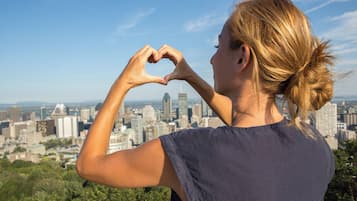Una persona forma un corazón con las manos, observando un paisaje urbano con varios edificios.