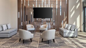 A modern hotel lobby with a large flat-screen TV, two sofas, and a patterned carpet. - Staybridge Suites Montréal Airport - St-Laurent by IHG (Montreal)
