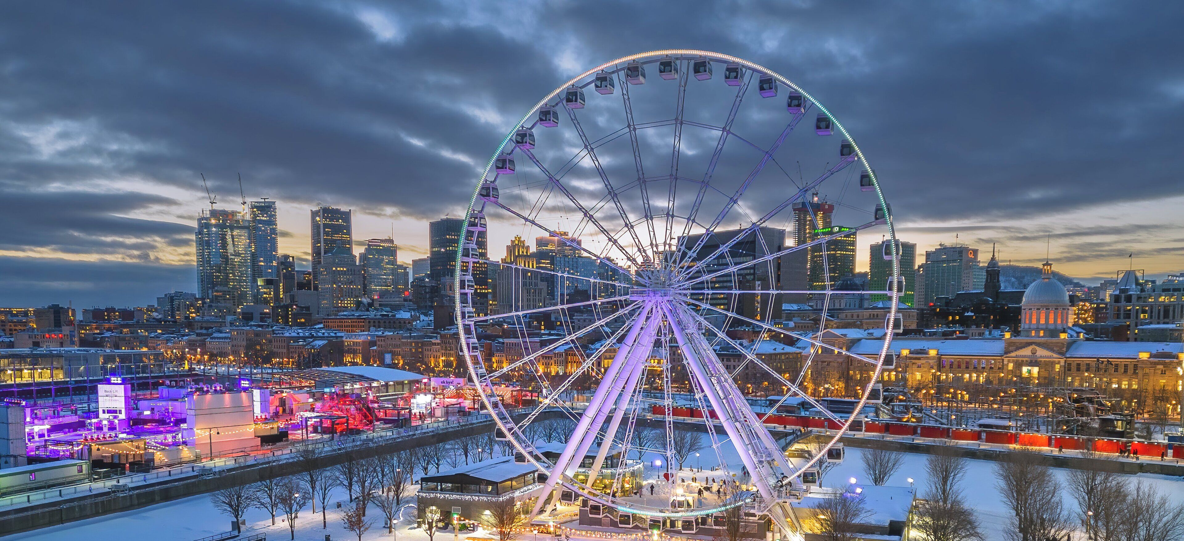 Une grande roue dominant un paysage urbain au crépuscule.