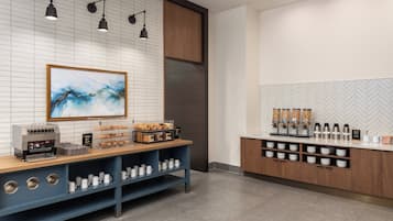 A modern coffee station with a coffee machine, pastries, and a coffee dispenser.