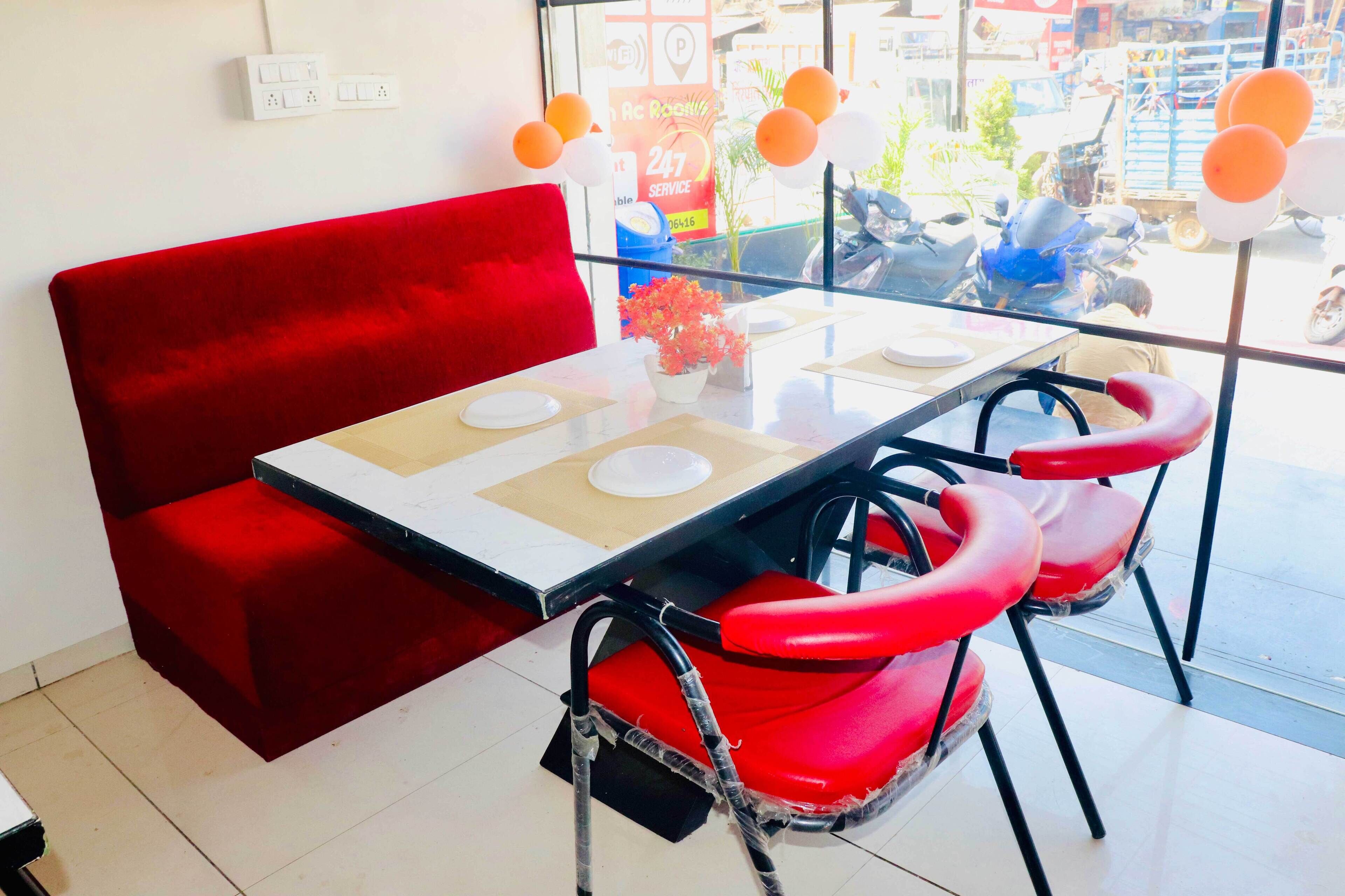 Un canapé rouge et une table avec des chaises se trouvent dans une pièce donnant sur la rue.