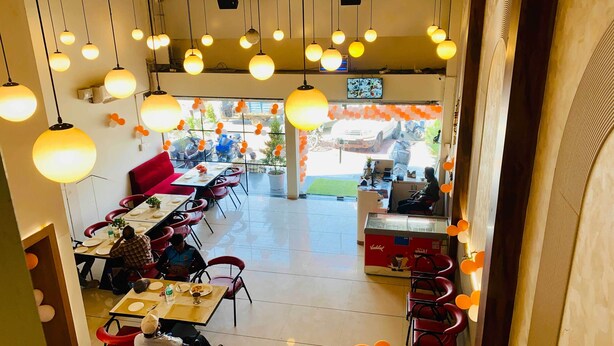 A restaurant with round tables, red chairs, and hanging spherical lights.