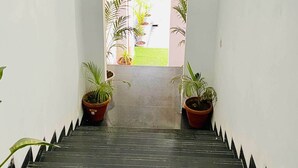 A staircase with potted plants on either side, leading to a bright outdoor area.