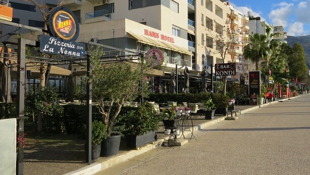 Eine Straße mit einer Pizzeria namens "La Nonna" und einem Hotel namens "Haris Hotel".