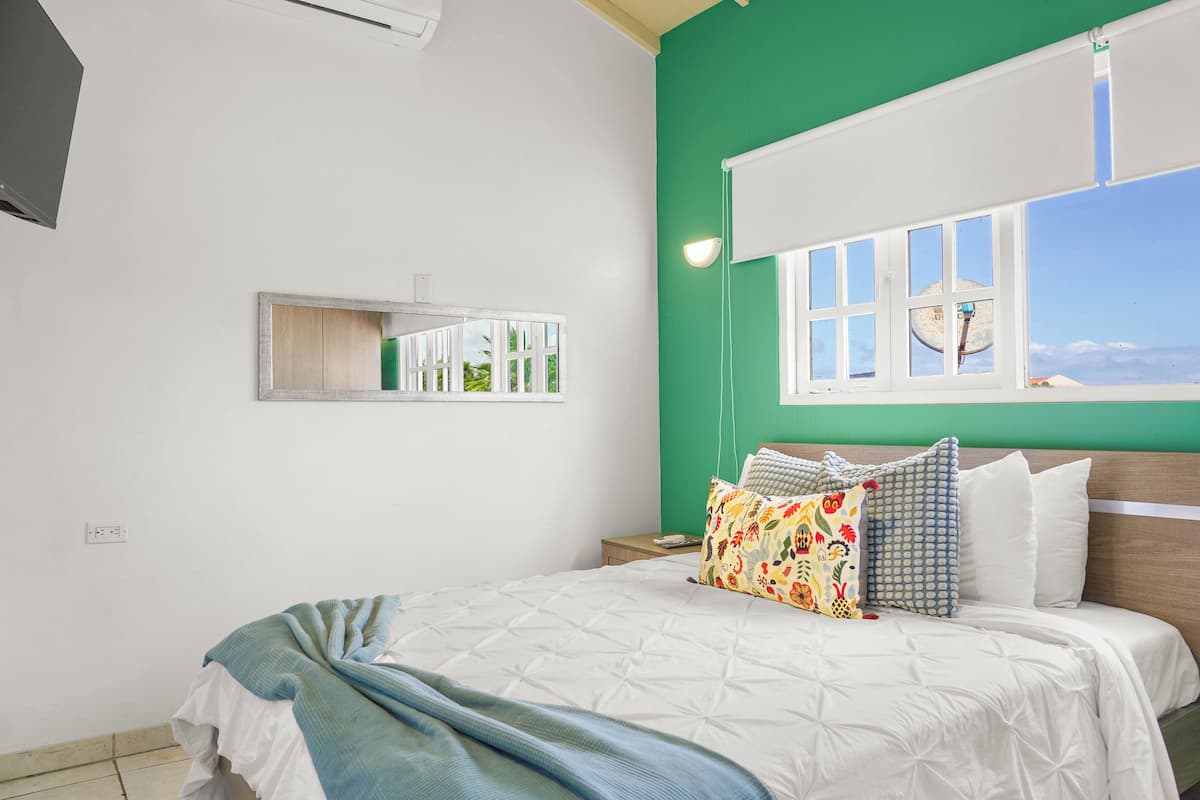 Een slaapkamer met een bed, een raam met uitzicht, een spiegel en een nachtkastje.