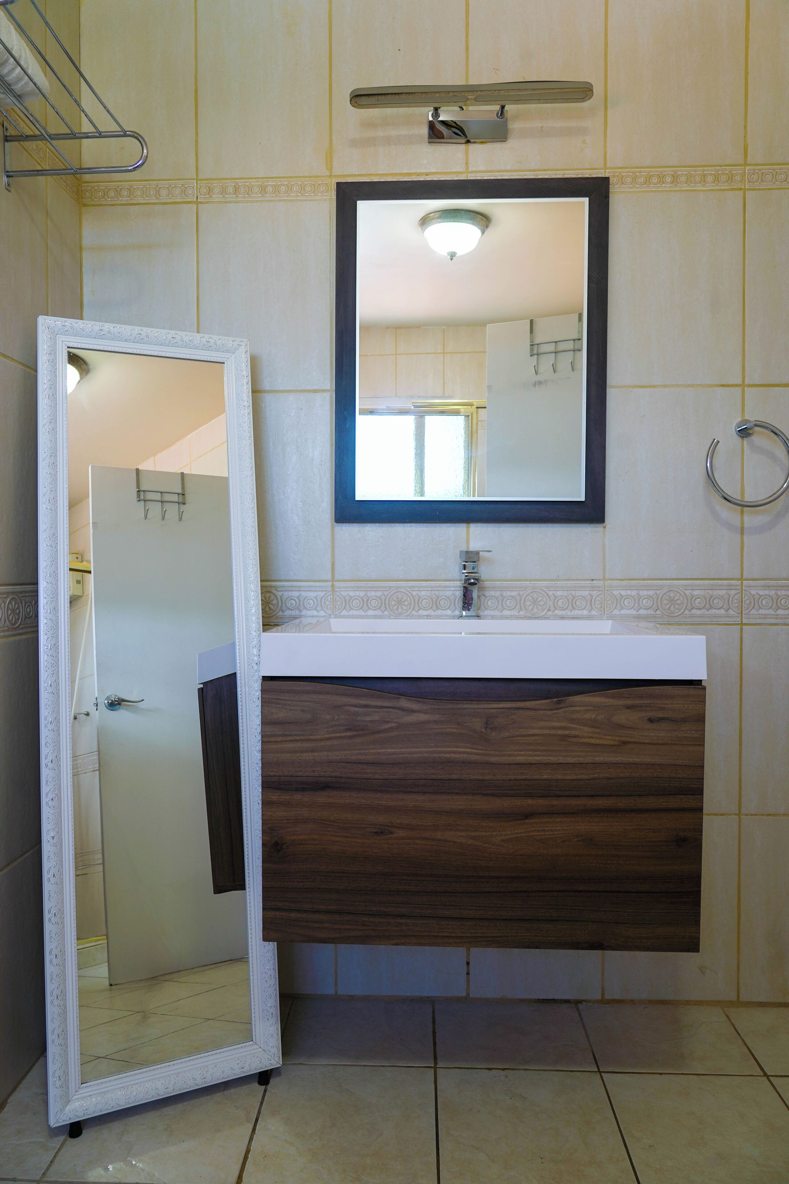 A bathroom with a white vanity, a mirror, and a wooden cabinet.