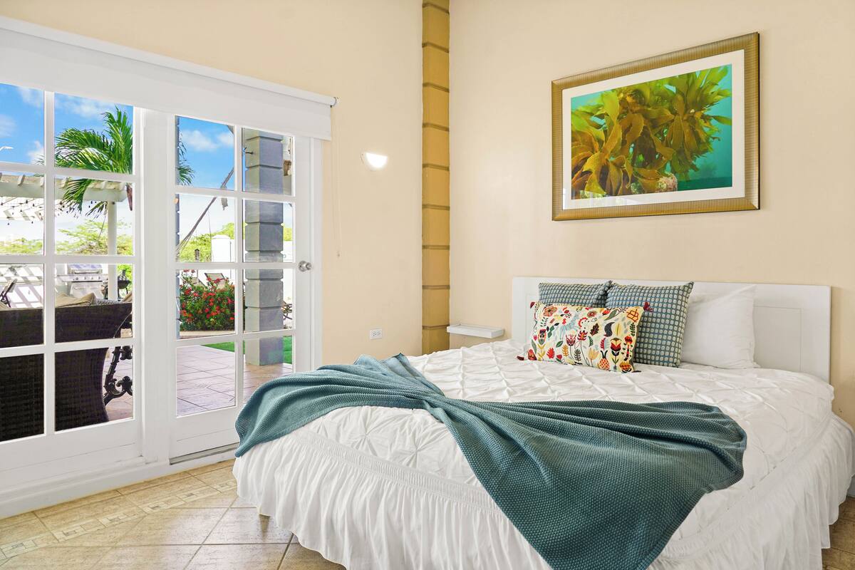 Een slaapkamer met een bed, een raam met uitzicht op de omgeving en een schilderij aan de muur.