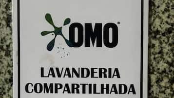 Un letrero con el texto 'AQUI TEM LAVANDERIA COMPARTILHADA' y un logotipo.