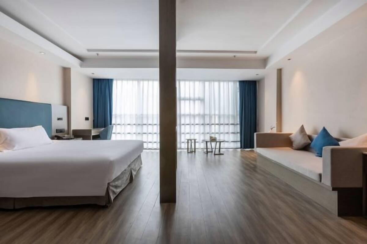 Una habitación de hotel con cama, sofá, escritorio y vistas a la ciudad.