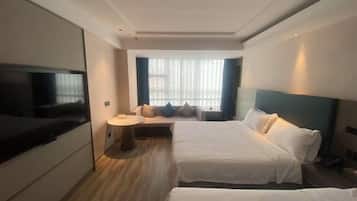 A hotel room with two beds, a TV, a small round table, and a window with curtains.