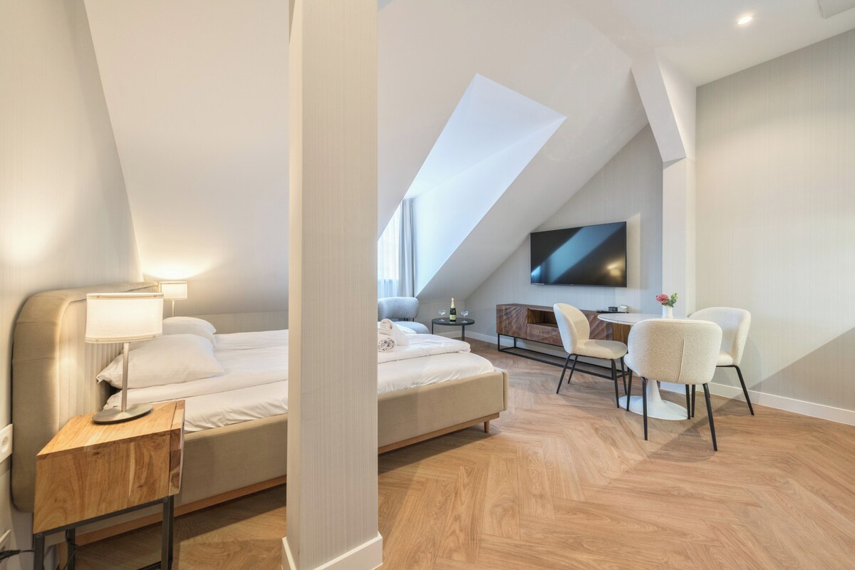 Un dormitorio moderno con una cama, mesita de noche, lámpara y televisor montado en la pared.