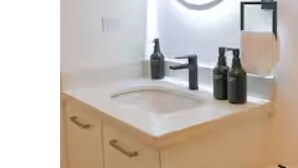 A modern bathroom with a round mirror, illuminated by a circular light, a sink, and a towel rack. - Cozy, Modern APT @ Col. Escalon - Pool, Gym, A/C (San Salvador)