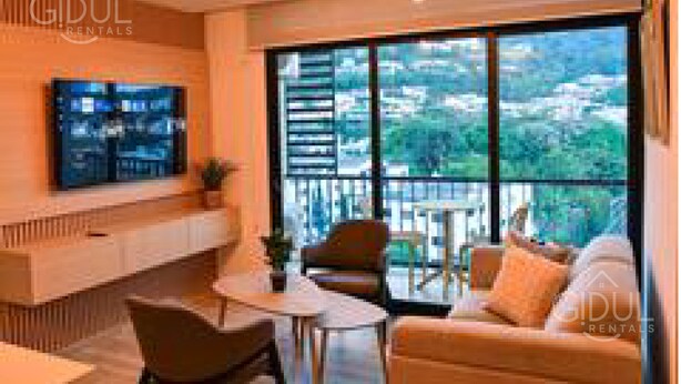 A modern living room with a large TV, comfortable seating, and a balcony with a city view. - Cozy, Modern APT @ Col. Escalon - Pool, Gym, A/C (San Salvador)