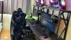 Um espaço de jogos com dois monitores, teclado, rato, cadeira gamer e iluminação RGB.
