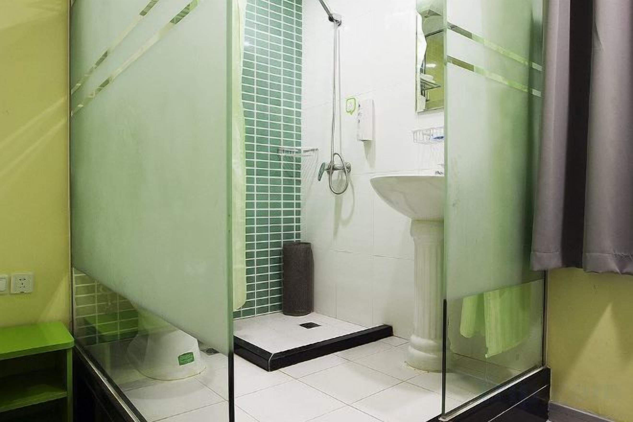 A bathroom with a glass shower enclosure, a white sink, and a tiled shower area.