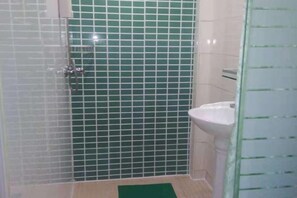 A bathroom with a shower, a sink, and a green-tiled wall. - Shanghai Jinchuan Hotel (Chuansha Metro Station) (Shanghai)