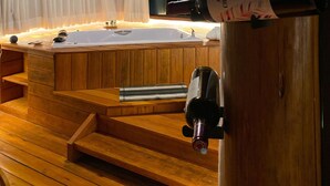 A wooden interior with a bathtub, a piano, and bottles of wine on a wooden stand. - Reserva Cipó (Santana do Riacho)