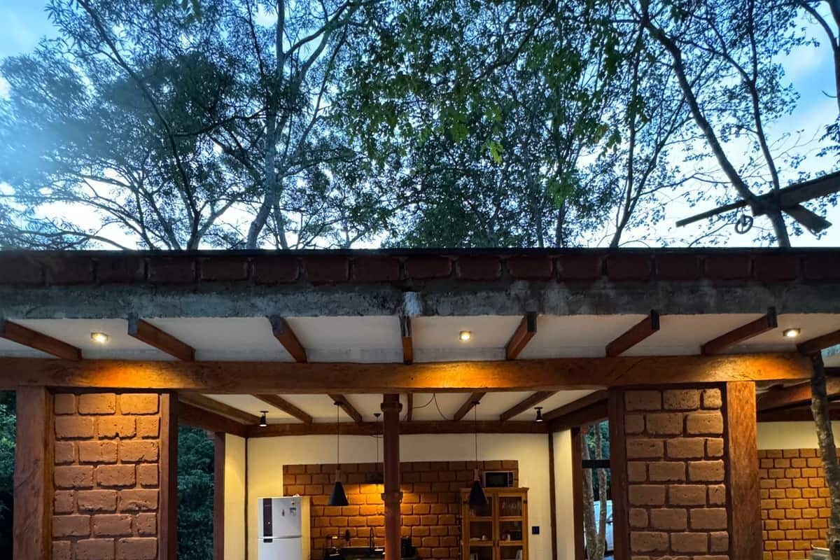An outdoor dining area with brick walls, a stone floor, and a view of trees.