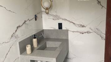 Et badeværelse med marmorvæg, en indbygget grå vask, toilet og et håndklædestativ.