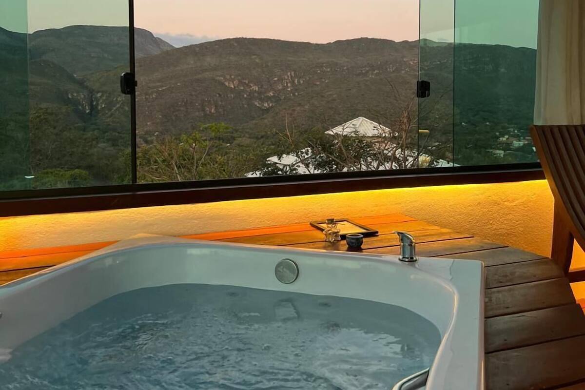A hot tub with a view of mountains through large glass windows.