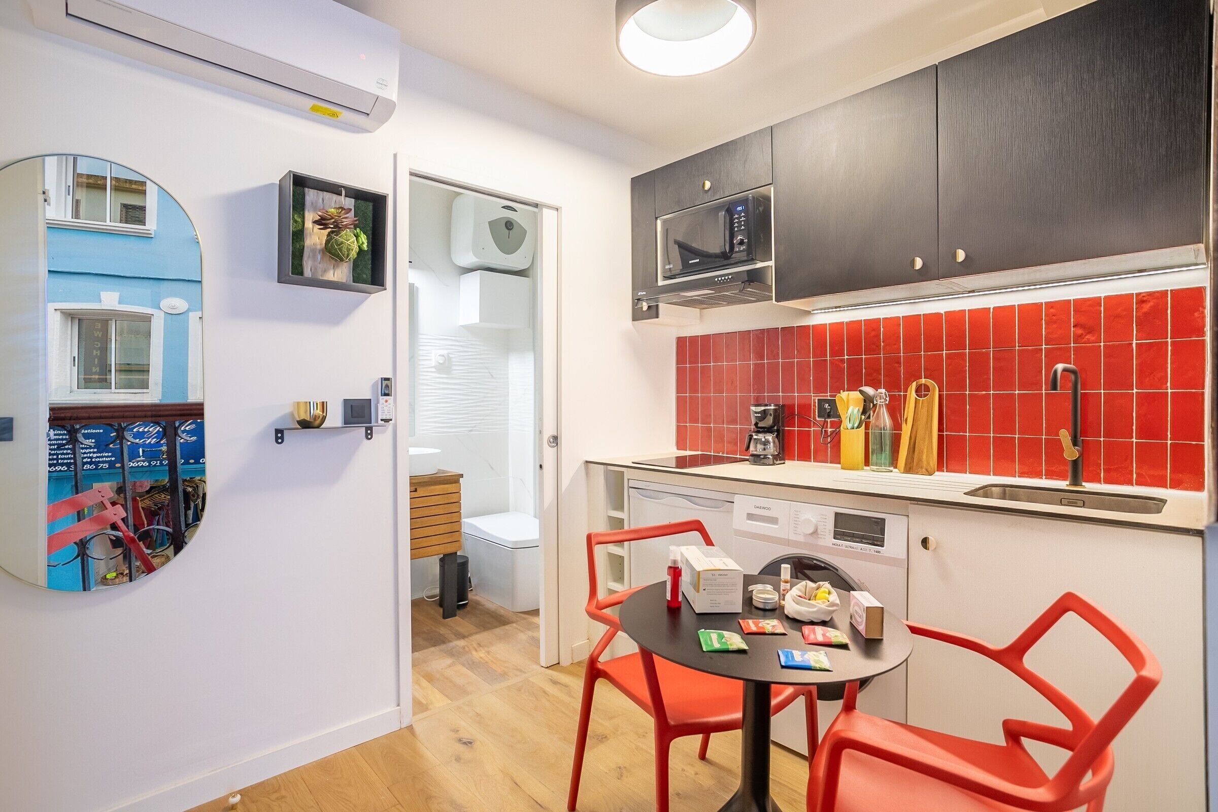 A compact kitchen with a microwave, coffee maker, and red-tiled backsplash.