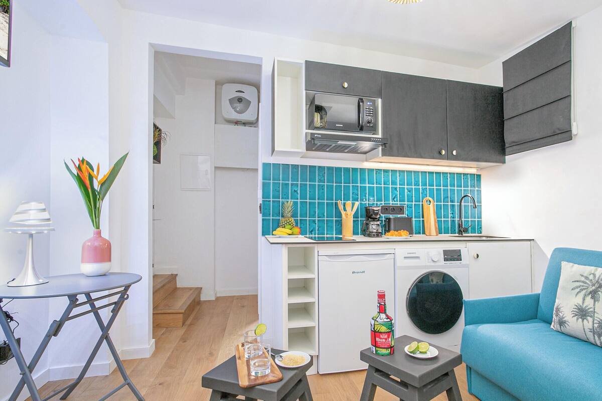 Un espacio habitable compacto con kitchenette, comedor y sofá.