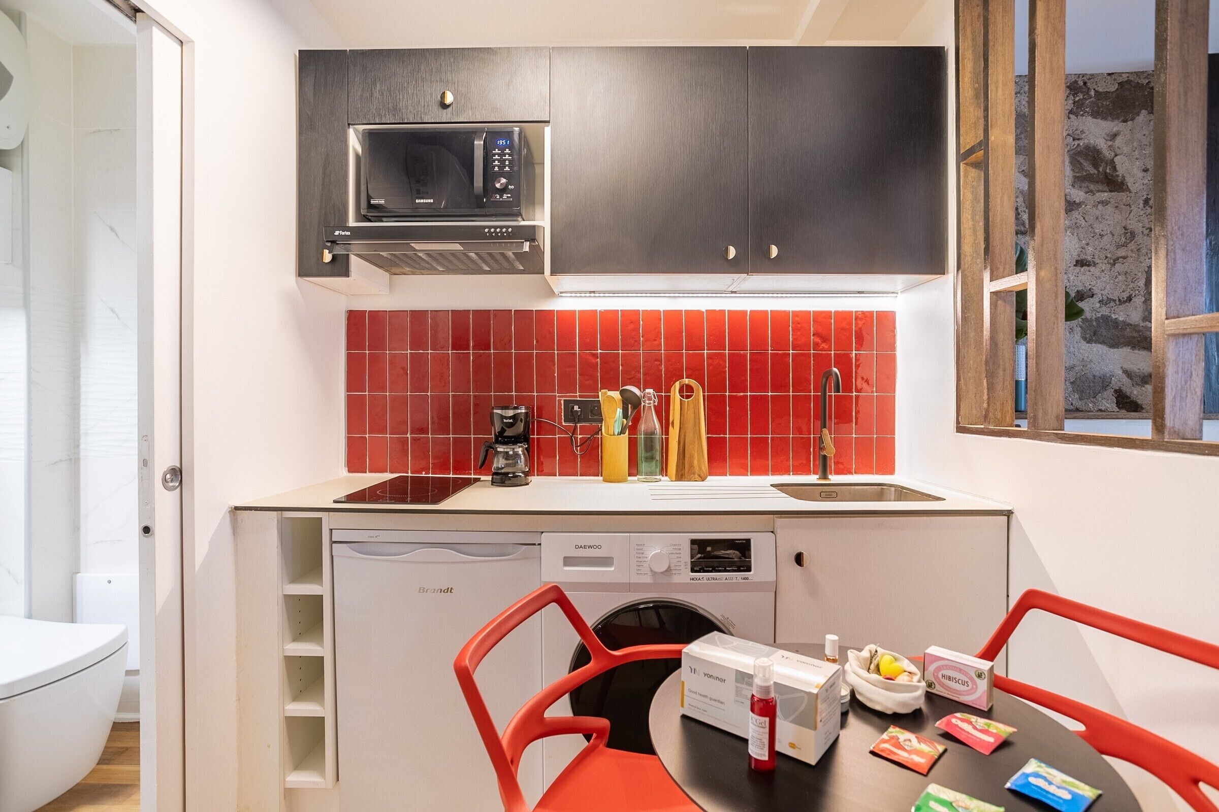 A compact kitchen with a microwave, coffee maker, and a sink.