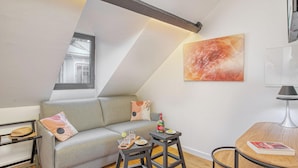 A modern living room with a grey sofa, a small wooden table, and a painting on the wall. - Residence Nokoshima (Fort-de-France)