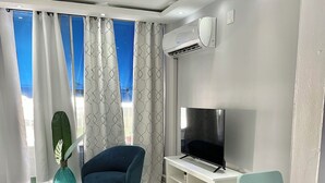 A modern living room with a blue chair, a TV, and a white entertainment unit.
