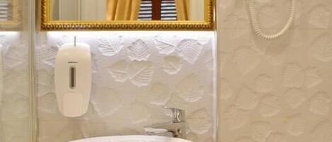 A bathroom with a white sink, a gold-framed mirror, a handheld hair dryer, and a towel rack.