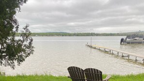 Een gazon met twee houten Adirondack-stoelen gericht op een meer.
