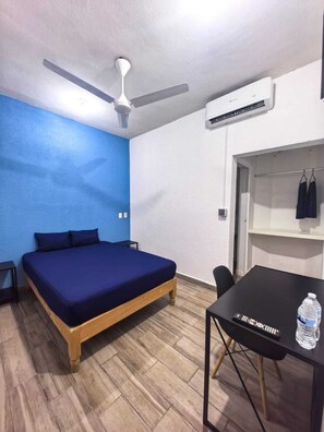 Cozy retreat with a single bed, ceiling fan, and air conditioning unit, perfect for a restful stay.