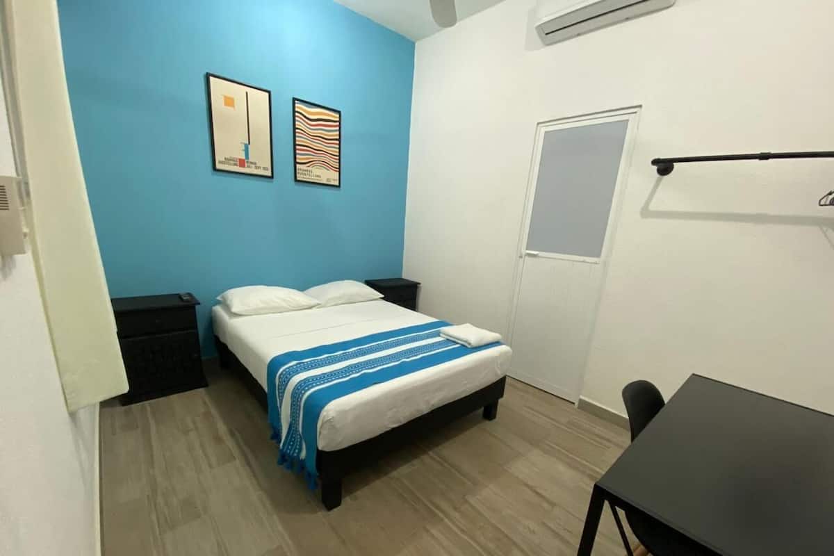 A bedroom with a bed, a nightstand, a desk, and two wall art pieces.