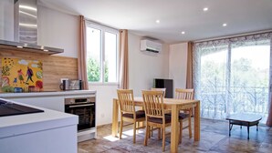 A modern kitchen with a dining area, including a table and chairs, a microwave, and an oven. - Les Mûriers (Calvi)