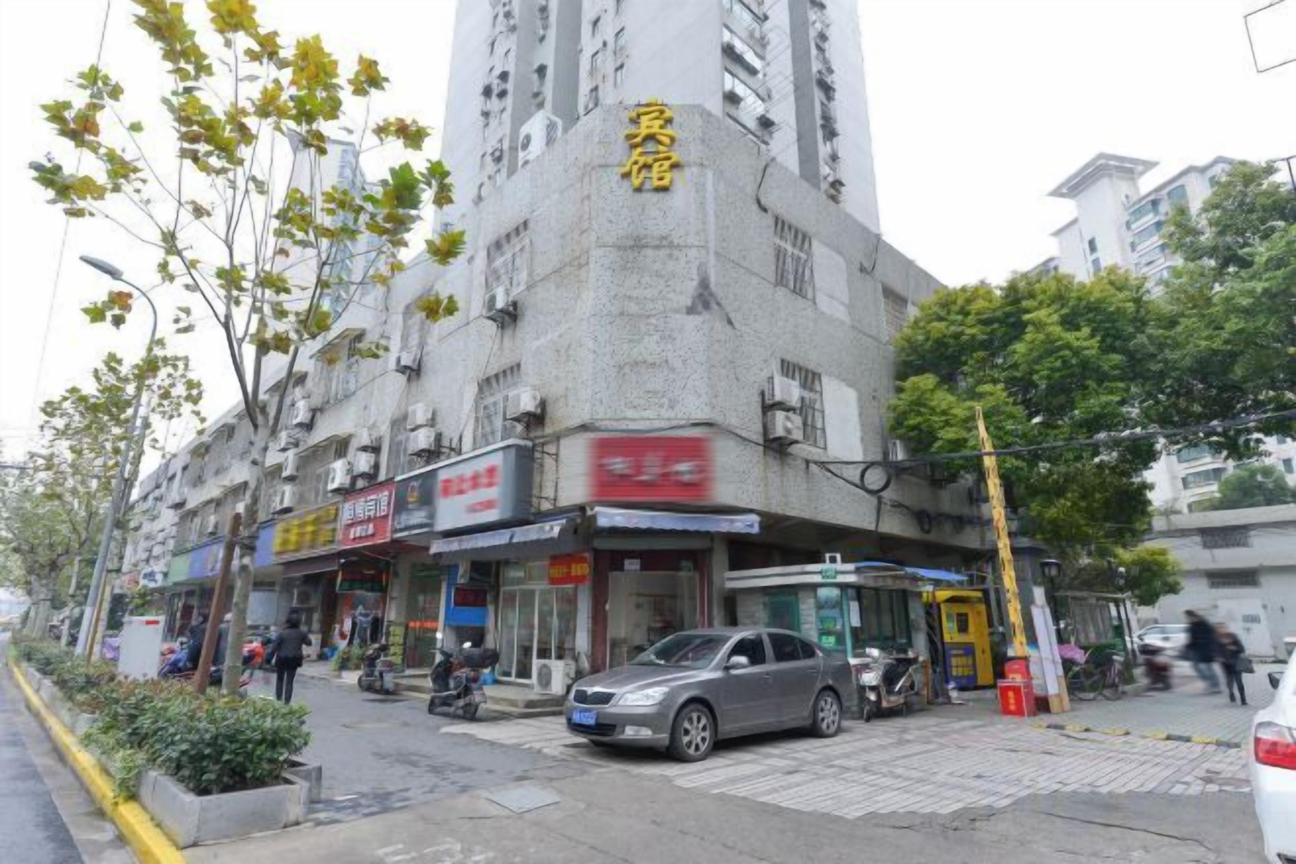 Un edificio de varios pisos con locales comerciales en la planta baja, incluyendo una farmacia y un restaurante.