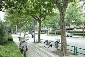 A tree-lined sidewalk with a parked scooter and a bicycle. - Hengbo Hotel (Shanghai)