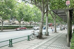 A sidewalk with a bicycle, a pedestrian, and a street with cars. - Hengbo Hotel (Shanghai)