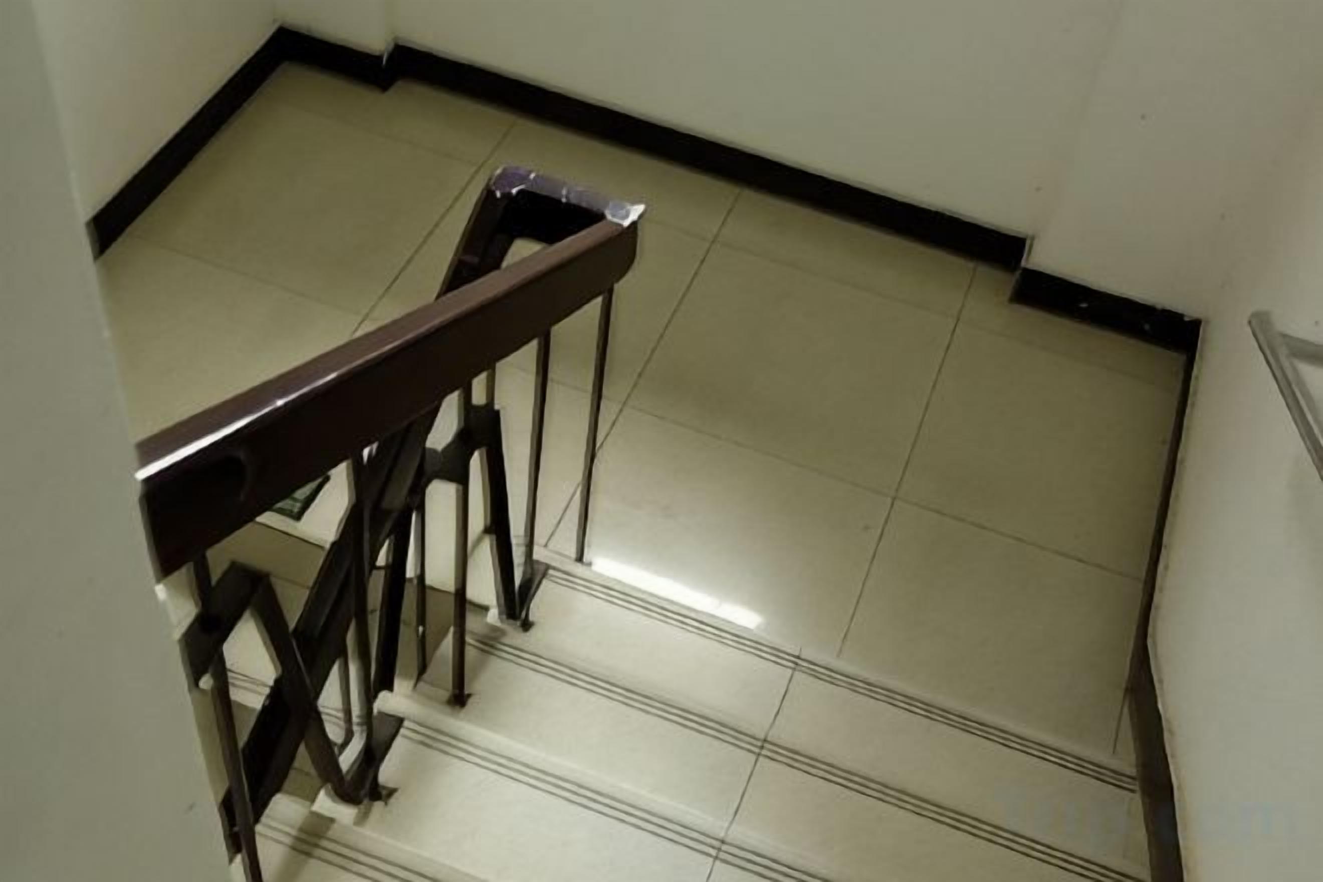 A staircase with a handrail and a tiled floor.