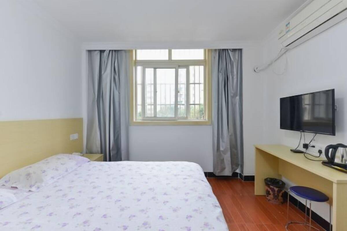 Une chambre d’hôtel avec un lit, une télévision, un bureau et une fenêtre avec des rideaux.