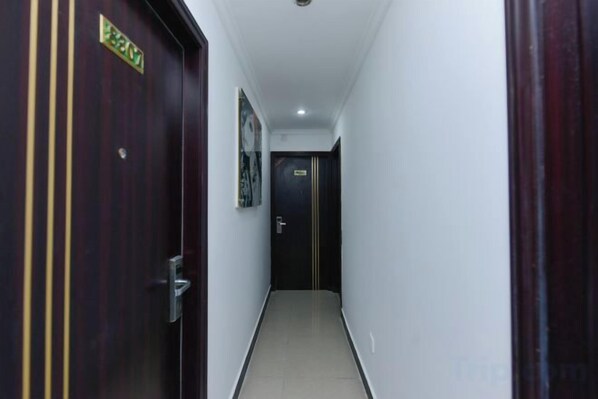A narrow hallway with a wooden door on the left and a dark door at the end.