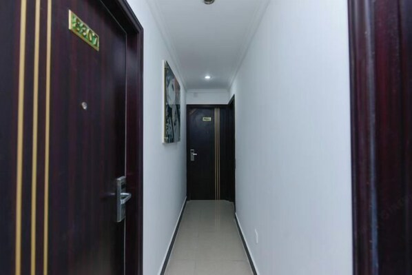 A narrow hallway with a wooden door on the left and a black door at the end. - Hengbo Hotel (Shanghai)