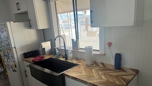 A kitchen with a built-in sink, wooden countertop, white cabinets, and a window with a view of the outside. - 2-bedroom mobile home in enchanting Havasu Lake with WiFi, AC (Havasu Lake)