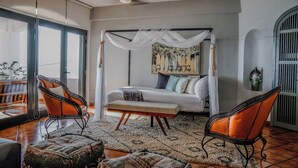 A bedroom with a four-poster bed, a ceiling fan, and a large window. - Villa Cobojo (Bucerías)