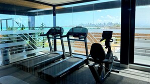 Una palestra con tapis roulant e un nastro trasportatore, ampie finestre con vista sulla città.