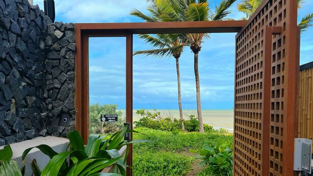 Un muro di pietra, un cancello di legno e vista sulla spiaggia.