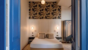 A bedroom with a bed, two bedside tables, a wall-mounted light fixture, and a patterned wallpaper. - Modern Designer 2BR Apartment – Walk to Sea (Sliema)