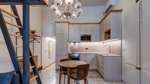 A modern kitchen with a dining area, featuring a chandelier, a stove, and cabinets. - Modern Designer 2BR Apartment – Walk to Sea (Sliema)
