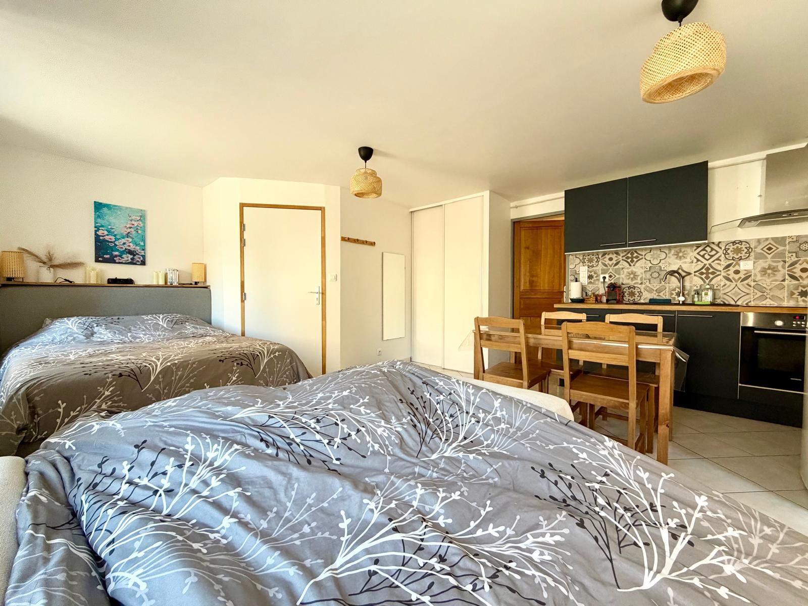 A compact room with two beds, a dining table, and a kitchenette.
