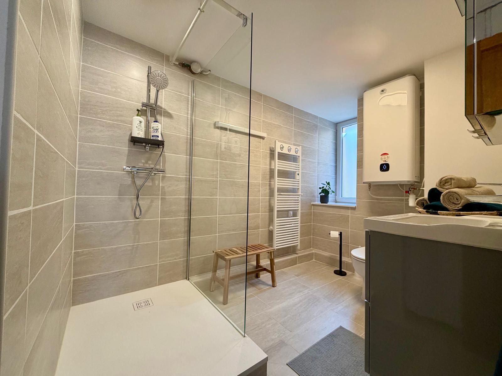 Ein modernes Badezimmer mit einer Duschkabine aus Glas, einem weißen Waschbecken und einem Handtuchhalter.